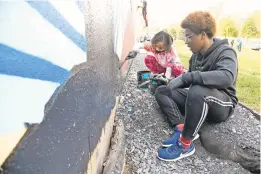  ??  ?? Maiya Okedeyi, 10, and her brother Imran Okedeyi, 15, paint the mural as part of a group from the Box of Rain program.