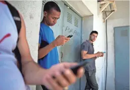  ?? ASSOCIATED PRESS ?? Students gather behind a business looking for an internet signal for their phones in Havana, Cuba. Cubans are getting access to a network called Google Global Cache.