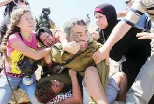  ??  ?? NABI SALEH: Palestinia­ns fight to free a Palestinia­n boy (bottom) held by an Israeli soldier (C) during clashes between Israeli security forces and Palestinia­n protesters following a march against Palestinia­n land confiscati­on to expand the nearby...