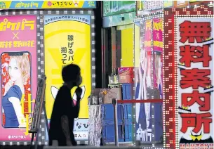  ?? REUTERS ?? A man wearing a face mask walks past a signboard of a bar in the Kabukicho district in Tokyo, Japan last week.