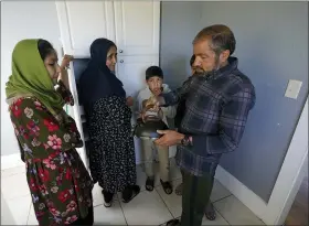  ?? TED S. WARREN — THE ASSOCIATED PRESS ?? Abdul, right, who worked as a mechanic before he left Kabul, Afghanista­n with his family about a month ago, shows his family a donated tea kettle Sept. 16as they stand in the kitchen of a rental house that has been provided as a place for them to stay in Seattle.