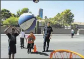  ??  ?? Clark County Fire Department firefighte­r Frank Consiglio plays basketball with neighborho­od children.