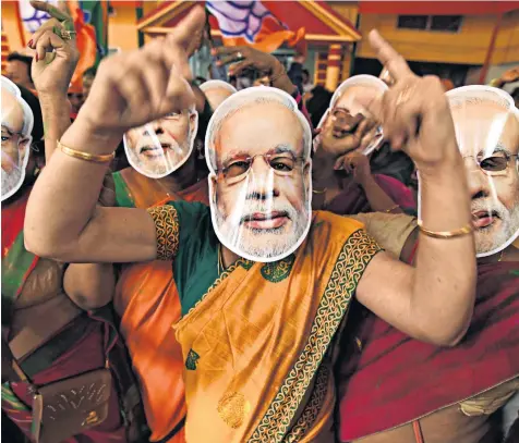  ??  ?? Celebratin­g the victory, Modi supporters wore masks of their hero’s face. Top, Mr Modi with his right-hand man and party president Amit Shah
