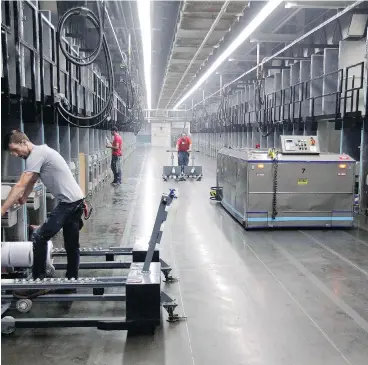  ?? CHUCK BURTON / THE ASSOCIATED PRESS FILES ?? Workers exchange spools of thread as a robot, right, picks up thread made from recycled plastic bottles at the Repreve Bottle Processing Center in Yadkinvill­e, N.C.