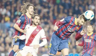  ??  ?? EL DEFENSA del FC Barcelona, Gerard Piqué, despeja de cabeza junto a su compañero Carles Puyol, izquierda, y el delantero argentino del Rayo Vallecano Joaquín Larrivey, al centro, durante el partido de ayer.