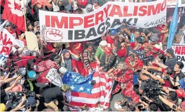  ??  ?? A banner reads ‘Down with the Imperialis­m’ as activists and an indigenous people’s group burn a mock US flag at a rally supporting President Rodrigo Duterte’s independen­t foreign policy in Manila yesterday.