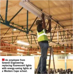  ?? ?? An employee from GreenX Engineerin­g replacing fluorescen­t lights with energy-saving lights at a Western Cape school.