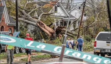  ?? PHOTOS BY JOHN SPINK/JOHN.SPINK@AJC.COM ?? Work crews and residents survey the damage on Lagrange Street in Newnan from storms that rolled through Coweta County and other parts of Georgia overnight Thursday.