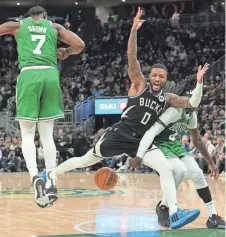  ?? MARK HOFFMAN /MILWAUKEE JOURNAL SENTINEL ?? Boston Celtics guard Jrue Holiday, right, knocks the ball away from Milwaukee Bucks guard Damian Lillard during the second half Tuesday at Fiserv Forum in Milwaukee.