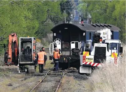  ?? PHOTO: LINDA ROBERTSON ?? Back on track . . . Operations staff and contractor­s work to return a Taieri Gorge Railway carriage to the tracks after it derailed in North Taieri yesterday.