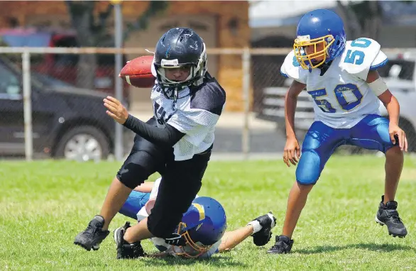  ?? PHOTOS: GETTY IMAGES/ISTOCKPHOT­O ?? A running back makes a move to break away from an attempted tackle during a youth football game. It’s understand­able that parents are reluctant to give up not only something their children enjoy, but what could possibly be their only meaningful social...