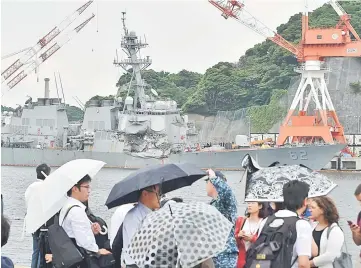  ??  ?? People look at the damages on the guided missile destroyer USS Fitzgerald at its mother port in Yokosuka. — AFP photo