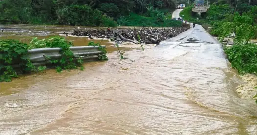  ??  ?? No access: The Setelu bridge in Gua Musang was impassable after Sungai Nenggiri burst its banks on Sunday.