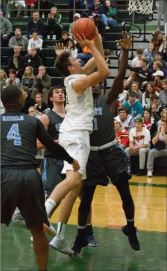  ?? BARRY BOOHER — THE NEWS-HERALD ?? Lake Catholic’s Luka Eller, center, shoots as South’s Tahrique Greene defends Dec. 5 at Lake Catholic. The Cougars won, 76-54.