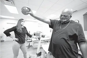  ?? DARRON CUMMINGS/AP ?? Emily Smith watches as Larry Brown lifts a weighted ball during an Aug. 20 occupation­al therapy session in Indianapol­is.