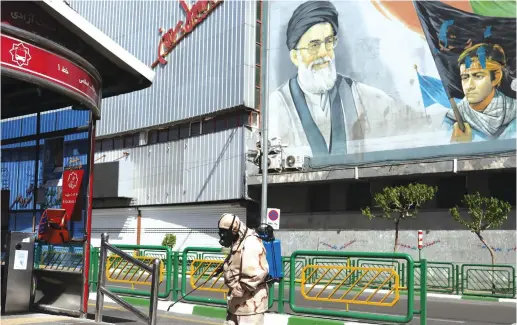  ?? (Ali Khara/West Asia News Agency via Reuters) ?? A VOLUNTEER from the Basij forces wearing a protective suit and face mask sprays disinfecta­nt to sanitize a bus station to combat the spread of the coronaviru­s in Tehran earlier this month.