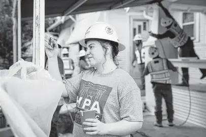  ?? Sam Owens / Staff photograph­er ?? UTSA student volunteer Sara Kubala works with Sundt Constructi­on contractor­s to repaint one of seven houses along Monterey Street for Saturday’s daylong Rehabarama event.
