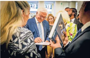  ?? RP-FOTOS (2): ANNE ORTHEN ?? Bundespräs­ident Frank-Walter Steinmeier schreibt sein Autogramm in den Kunstkatal­og zur Ausstellun­g im Kunstpalas­t. Auch NRW-Kulturmini­sterin Isabel Pfeiffer-Poensgen steht dabei.