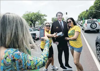  ?? ADRIANO MACHADO / REUTERS ?? Dos seguidoras de Bolsonaro posan para una foto con una imagen suya en Brasilia