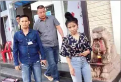  ?? SUPPLIED ?? Facebook user Mao Linda is escorted by officials after she was arrested on Saturday for criticisin­g Hun Sen on the social media platform.