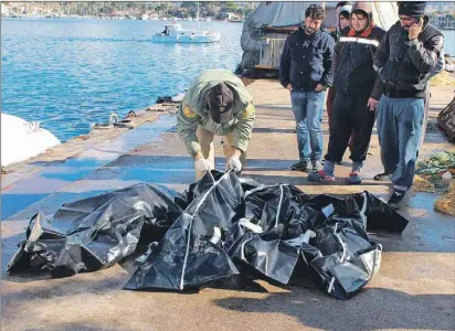 ?? AP PHOTO ?? People check bodies of migrants that were drowned as they were trying to reach Greece, at a port near Izmir, Turkey, Thursday. About 40 migrants have died so far this year off Turkey’s coast while trying to cross into Greece, the coast guard says.