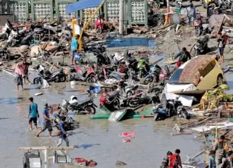  ?? AP PHOTO/TATAN SYUFLANA ?? People survey damage Sunday outside a shopping mall following earthquake­s and a tsunami in Palu, Central Sulawesi, Indonesia.