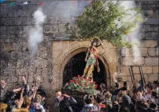  ?? ?? The carving of St. Sebastian is greeted with salutes of honor Jan. 21 while carried by worshipper­s during the festival.