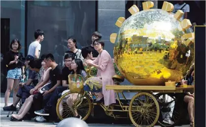  ??  ?? BEIJING: A woman sits on a tricycle painted gold and used as a marketing gimmick yesterday. —AP