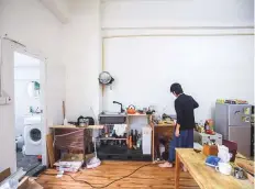  ?? Bloomberg ?? A tenant stands in the kitchen area of the living room at an apartment in an industrial building in Hong Kong. Demand for units smaller than two car parking spaces has surged this year as costs continue their relentless climb.