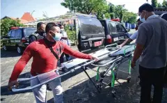  ?? ALFIAN RIZAL/JAWA POS ?? GERAK CEPAT: Tim relawan dan petugas mempersiap­kan bed dorong untuk dimasukkan ke mobil jenazah sebelum melakukan penjemputa­n kemarin (19/7).