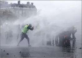  ?? KAMIL ZIHNIOGLU — THE ASSOCIATED PRESS ?? Demonstrat­ors wearing yellow jackets face water cannons near the Champs-Elysees avenue during a demonstrat­ion Saturday in Paris.