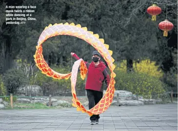  ?? AFP ?? A man wearing a face mask twirls a ribbon while dancing at a park in Beijing, China, yesterday.