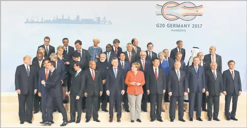  ??  ?? French President Emmanuel Macron (third left) leaves his position during the family picture to place himself next to Trump (left) as Merkel (centre) watches on the first day of the G20 meeting in Hamburg. — Reuters photo