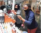  ?? JOE RONDONE/THE COMMERCIAL APPEAL ?? Evelyn Allen, left, helps customer Antoinette Simmons at Mahogany Essential Oils, a kiosk at the Oak Court Mall, on its second day after reopening Tuesday.