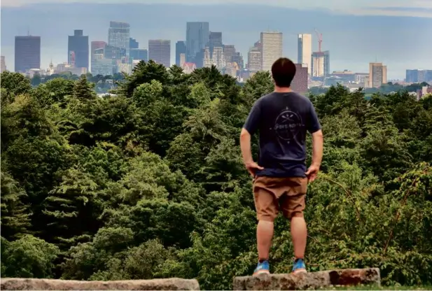  ?? JOHN TLUMACKI/GLOBE STAFF ?? Jay Strother paused to view the Boston skyline while hiking atop Peters Hill in the Arnold Arboretum recently.