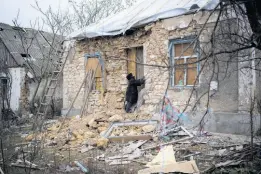  ?? AP PHOTOS ?? Oleksandra Hryhoryna inspects her house which was damaged by shelling last fall in Kalynivske, Ukraine.
