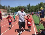  ?? ESTHER AVILA PHOTO BY ?? Noah Mayorga, a third-grader at Summit Charter Academy Lombardi, gets a helping hand from his father, Oscar Mayorga, as he crosses the finish line during the 2018 Special Olympics held at Bob Mathias Stadium in Tulare.