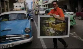  ??  ?? In this photo, Cuban fashion designer Mario Freixas poses for a photo as he walks among vintage american cars on a street in Havana, Cuba. Freixas, a well-known designer who dresses many of the stars of state-run television, sells shirts for $20 and...