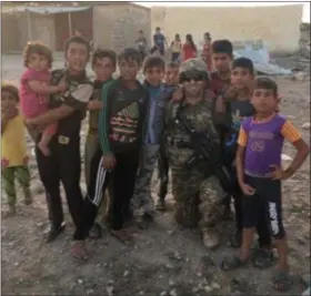  ?? COURTESY — HOPE FILIAGGI ?? Tyler Filiaggi poses with local children during his nine-month deployment to Iraq.