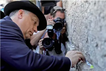  ??  ?? Photo ci-dessus : Le Premier ministre hongrois Viktor Orban place une note dans le mur ouest de la vieille ville de Jérusalem, le 20 juillet 2018, au cours d’une visite controvers­ée en Israël. Oubliant le discours parfois antisémite de Viktor Orban dans son pays, les deux leaders se sont entendus autour de leurs positions nationalis­tes et anti-immigratio­n. (© Menahem Kahana/AFP)