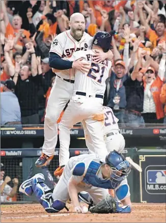  ??  ?? BRIAN McCANN (facing) celebrates with Derek Fisher, who scored the winning run in the 10th inning as the Astros recorded the 13-12 victory and took a 3-2 lead going back to Los Angeles.