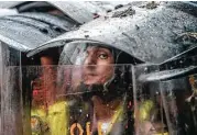  ?? Juan Barreto / AFP / Getty Images ?? Riot police take cover behind their shields Friday in Caracas as they clash with opposition activists protesting against the government.