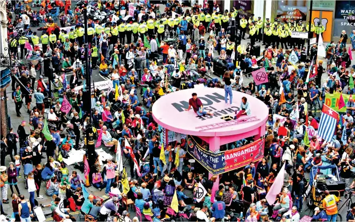  ??  ?? Focal point: Extinction Rebellion protesters caught police by surprise yesterday when they put up this giant pink table at a junction near London’s Covent Garden