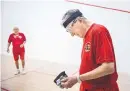  ??  ?? William “Bill” Matotan, right, a 95-yearold from Albuquerqu­e, removes his gloves after a match with Lake Westphal, pictured in the background, at the 33rd annual IRF World Senior Racquetbal­l Championsh­ips.
