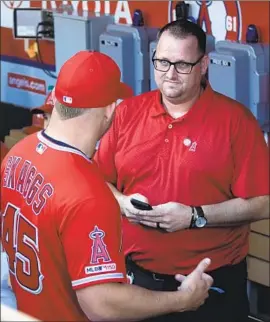  ?? John McCoy Getty I mages ?? ERIC KAY talks to Mike Trout, wearing a Skaggs jersey, in the dugout before the Angels honored Skaggs by no- hitting Seattle at Angel Stadium on July 12, 2019.