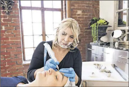  ?? PHOTOS BY EMILY BERL/THE NEW YORK TIMES ?? Makeup artist Dominique Bossavy demonstrat­es an eyebrow treatment with an employee in Beverly Hills, Calif. Semiperman­ent makeup has become one of the biggest trends in beauty as many women go to greater lengths to look as if they #wokeuplike­this.