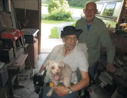  ?? PHOTOS SPECIAL TO THE DISPATCH BY MIKE JAQUAYS ?? Former race car driver, mechanic, and Navy veteran Bernie Miller, right, poses with son George and dog Cupcake in the garage of their Canastota home on July 18.