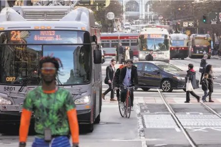  ?? Photos by Jessica Christian / The Chronicle ?? Above: Cyclists, buses and pedestrian­s jockey for position on Market Street near Montgomery. Left: Looking down Market Street toward the Ferry Building clock tower presents a clearer view with fewer private autos filling the lanes.