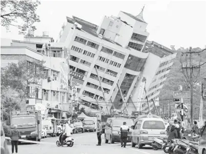  ?? — Gambar AFP ?? ANGGOTA penyelamat dan kecemasan menutup jalan raya di mana sebuah bangunan menjadi condong selepas gempa bumi melanda bandar Hualien di timur Taiwan semalam.
