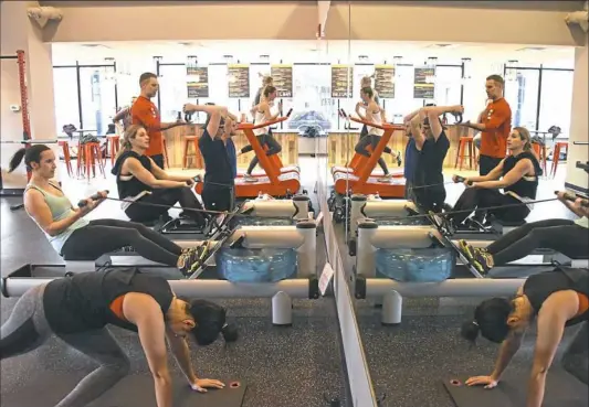  ??  ?? Gym owner and program developer Adam Cross monitors exercisers’ drills at 3 Minute Fitness on the South Side.